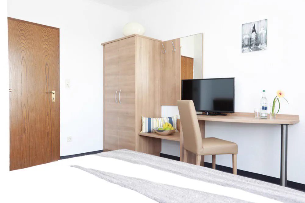 Gästezimmer mit Kleiderschrank, Schreibplatz und Flatscreen-TV