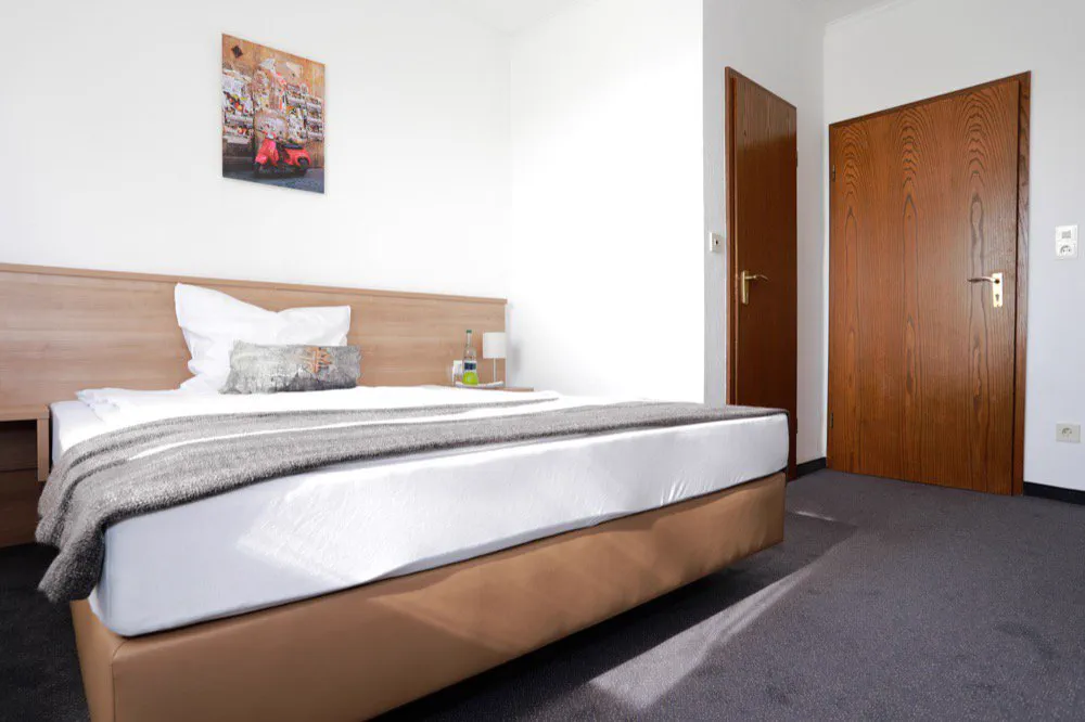 Blick über das Doppelbett zur Zimmertür