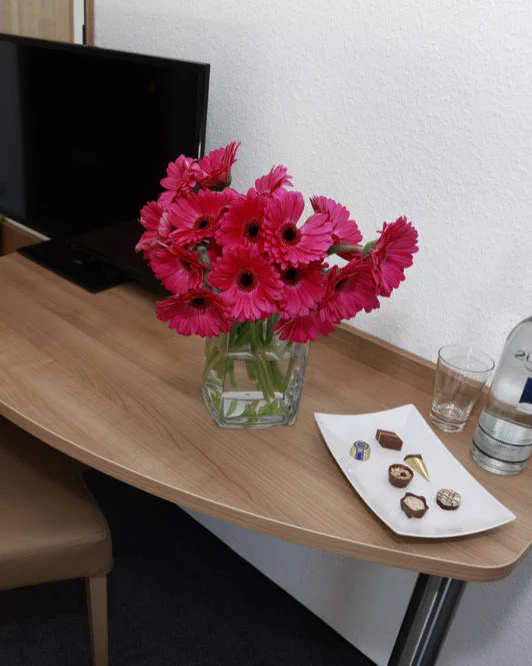 Frische Gerbera und Pralinen auf dem Schreibtisch eines Gästezimmers