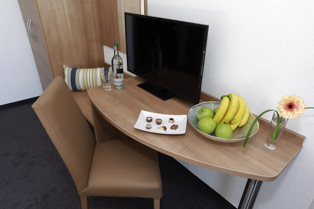 Schreibplatz im Gästezimmer mit Flatscreen-TV und Obstschale